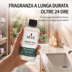 Una mano che regge il flacone di ricarica dell'olio profumato SÈVE White Tea in un bagno